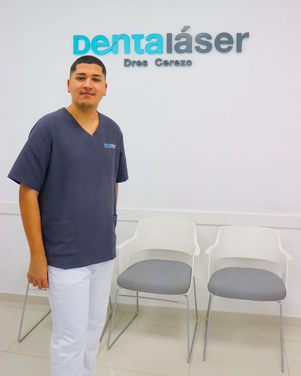 Miembro del equipo de recepción de Dentaláser junto al logo de la clínica